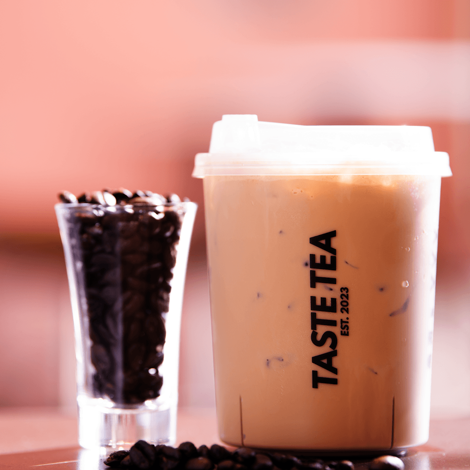 Iced Vietnamese coffee in a Taste Tea cup beside coffee beans